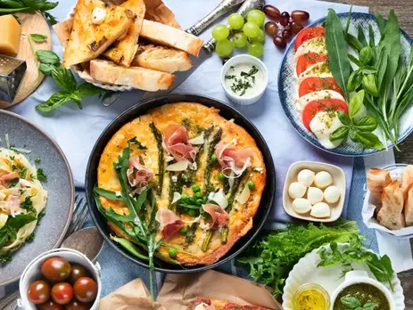 A table full of delicious Italian dishes like speck and bread and mozarella