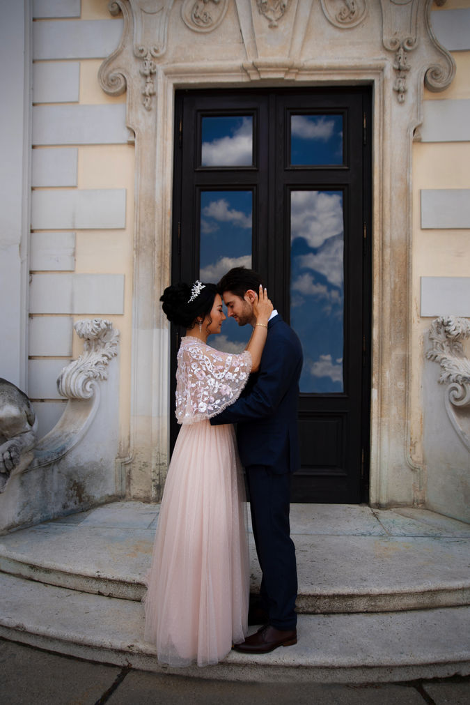 Ein Liebespaar stehend zusammen vor einer großen Tür in dem sich die Wolken spiegeln