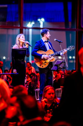 Live music duo in formal evening wear performing at a corporate award ceremony in a festive ballroom