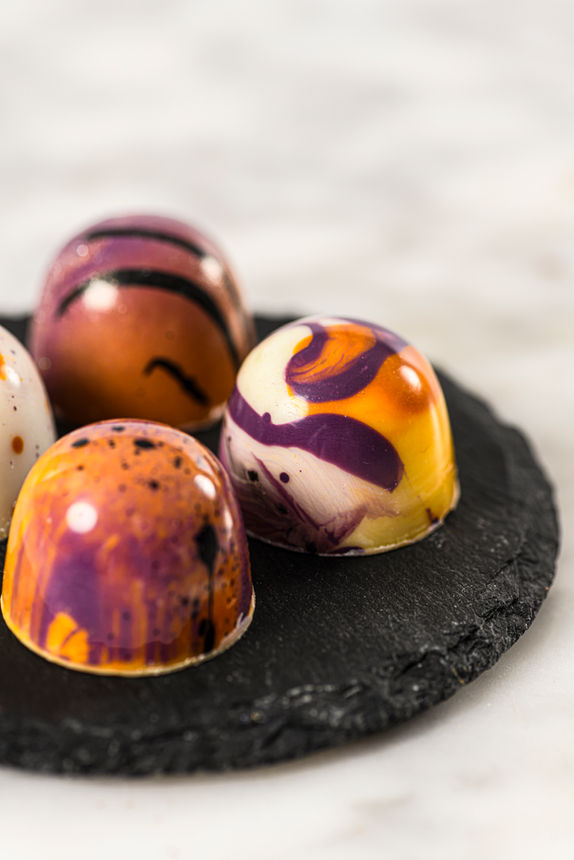 food photography of appetizing and colorful bonbons on a black dish