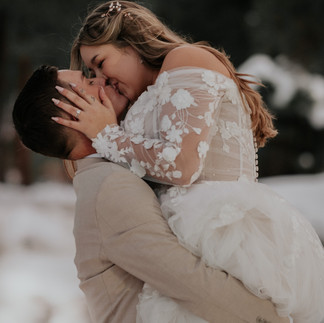 Groom lifts bride for a passionate kiss, bride holds grooms face as she kisses him