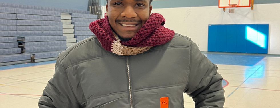 Student wearing a new coat and scarf that he picked out in the coat drive