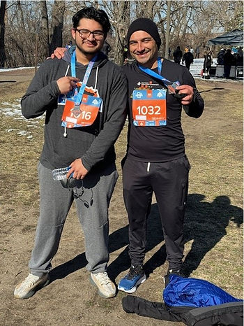 Luis Villar and one of his students smiling next to each other, holding up their race medals