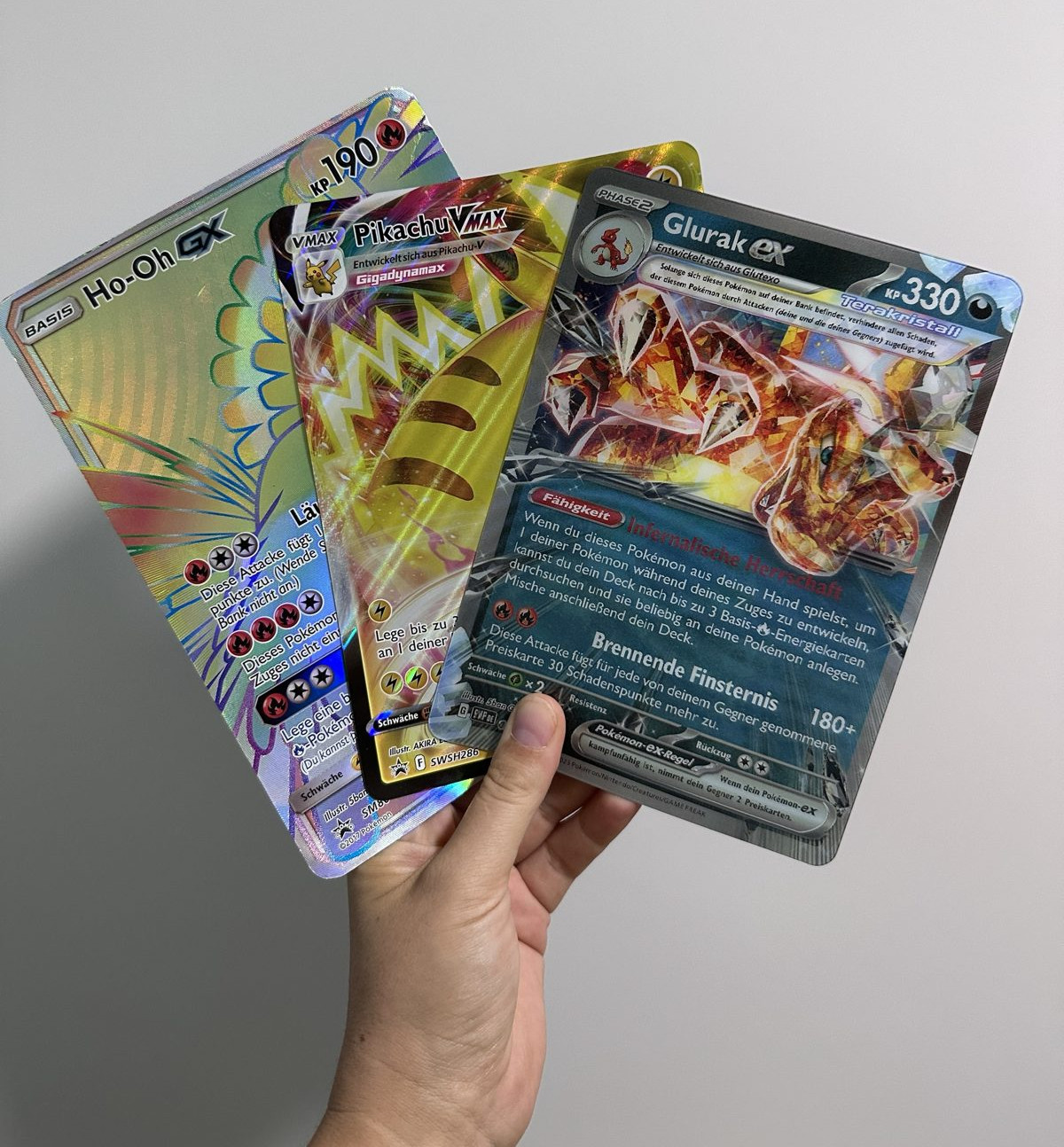 Drei große Pokémon-Karten: Glurak ex, Pikachu VMAX und Ho-Oh GX