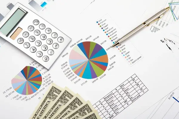 Calculator, financial charts, and cash on a desk, representing clean financial reports and visuals for making any decision related to funds or loans.