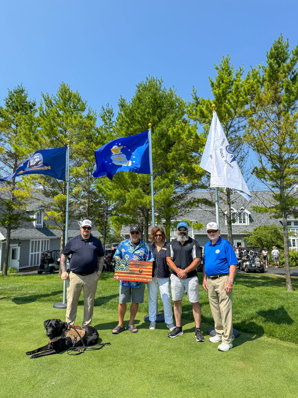 Sponsors posing with a therapy dog before the event starts on the golf course