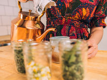 Woman pours tea with herbs in the foreground