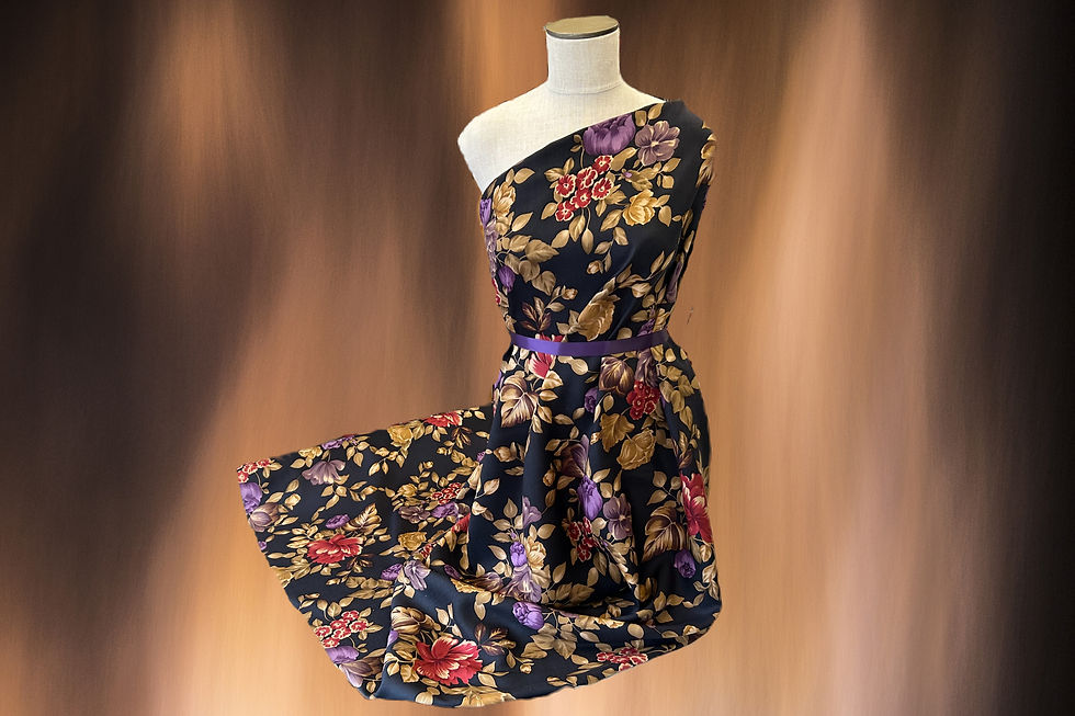 big floral pattern fabric in burgundy and purple on black ground draped on a mannequin with a hazy rust background
