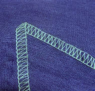 serged overlock edge of fabric aqua thread on purple fabric
