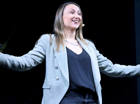 Abbie (also searched as Abbey or Abby) White against a dark background, with a big smile and arms outstretched mid-motion.