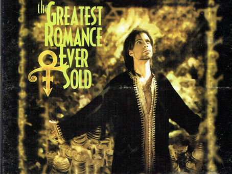 Prince, dressed in black and gold, stands before a microphone in a dramatic, treasure‑themed setting used for the single artwork of “The Greatest Romance Ever Sold.”