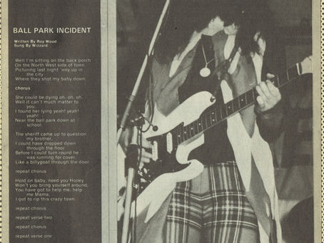 A Popswop Songwords page featuring the lyrics to “Ball Park Incident” on the left and a black‑and‑white photograph of Roy Wood performing onstage with guitar, face paint, and plaid trousers.
