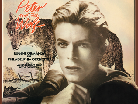 A vinyl record sleeve featuring a portrait of David Bowie with an illustrated wolf behind him. The record itself is bright yellow and partially visible beside the cover. Text on the sleeve credits Bowie as narrator and lists the Philadelphia Orchestra and conductor Eugene Ormandy, along with Britten’s Young Person’s Guide to the Orchestra.