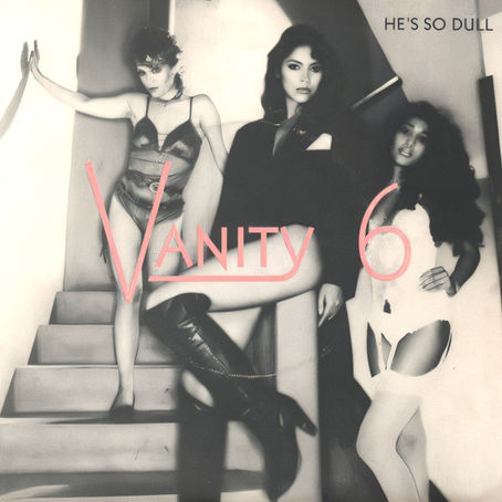 Black‑and‑white Vanity 6 cover featuring the trio posed on a staircase with bold pink “Vanity 6” lettering and the title “He’s So Dull.