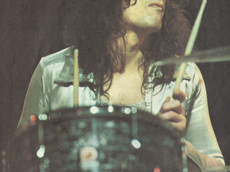 A full‑page Popswop feature showing Don Powell playing drums, wearing a shiny shirt, with his sticks raised mid‑performance. His name appears in bold yellow lettering beneath the image.