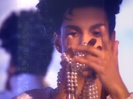 A still from Prince’s The Morning Papers video showing him seated at a piano with warm lighting, accompanied by Rosie Gaines, with additional scenes of dance, band performance, and children in a projection room.