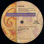 Paisley Park 12‑inch vinyl label for Prince’s 1988 single ‘Glam Slam’, showing remix credits, catalogue number 0‑21005, and paisley‑patterned label design.”Glam Slam was the second single to be released from Prince’s tenth album Lovesexy. It was released two months after the album, and received a release around the world. Like the previous single Alphabet St., the single was released in a clear sleeve with a stylized sticker, rather than traditional artwork. The b-side, Escape, was previously-unreleased.