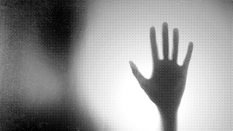 Silhouette d’une main derrière une vitre translucide