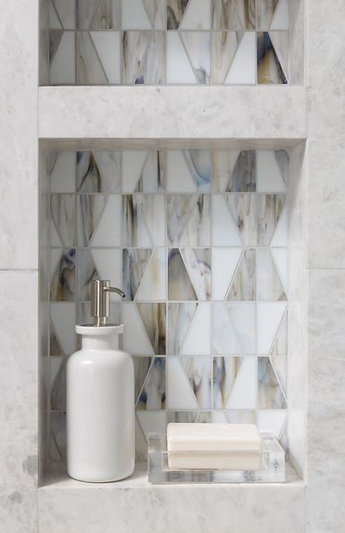 Marble shower niche with geometric tile and soap bottle.