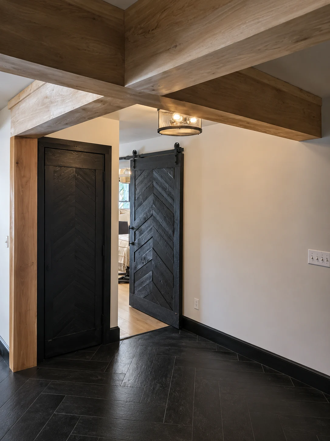 Renovated entry with wood ceiling beams, dark doors and tile flooring on South Street in Woodstock, Vermont.