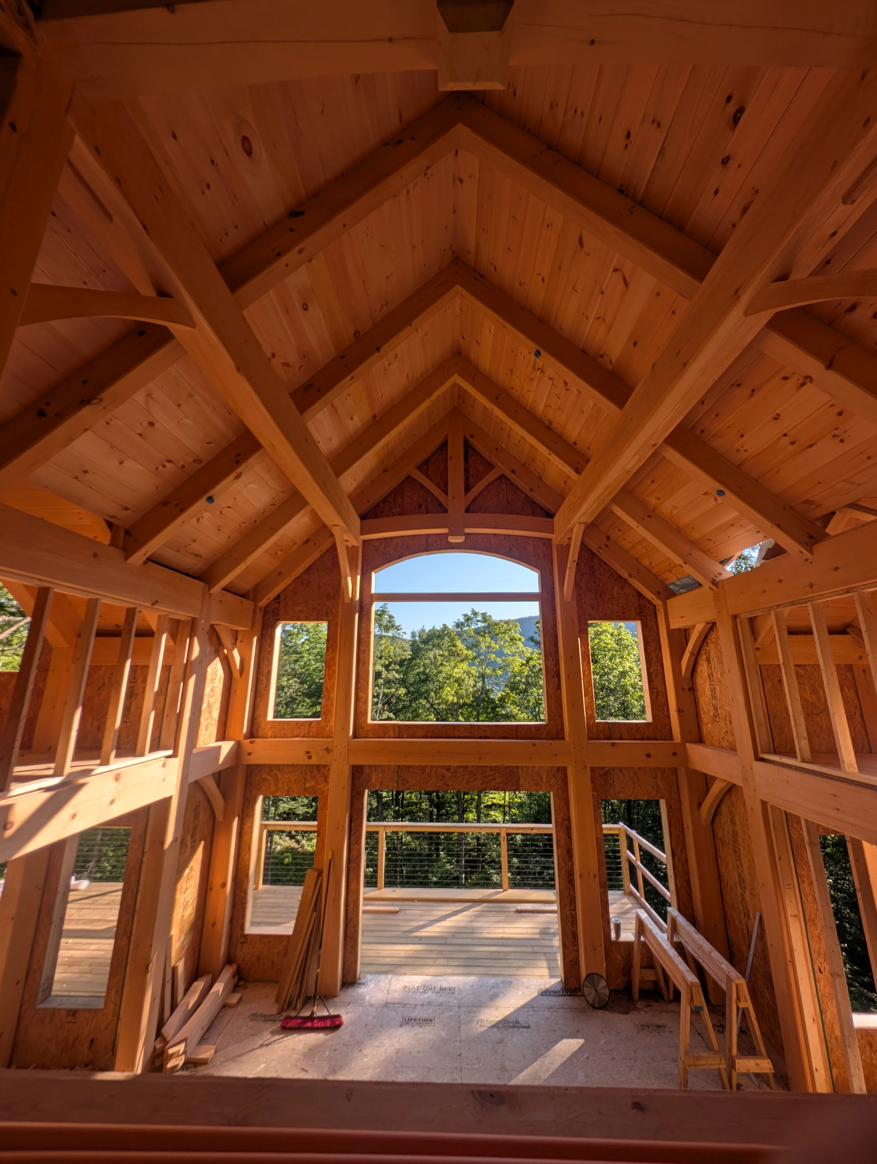 Exposed timber roof structure and wood framing inside a home under construction.