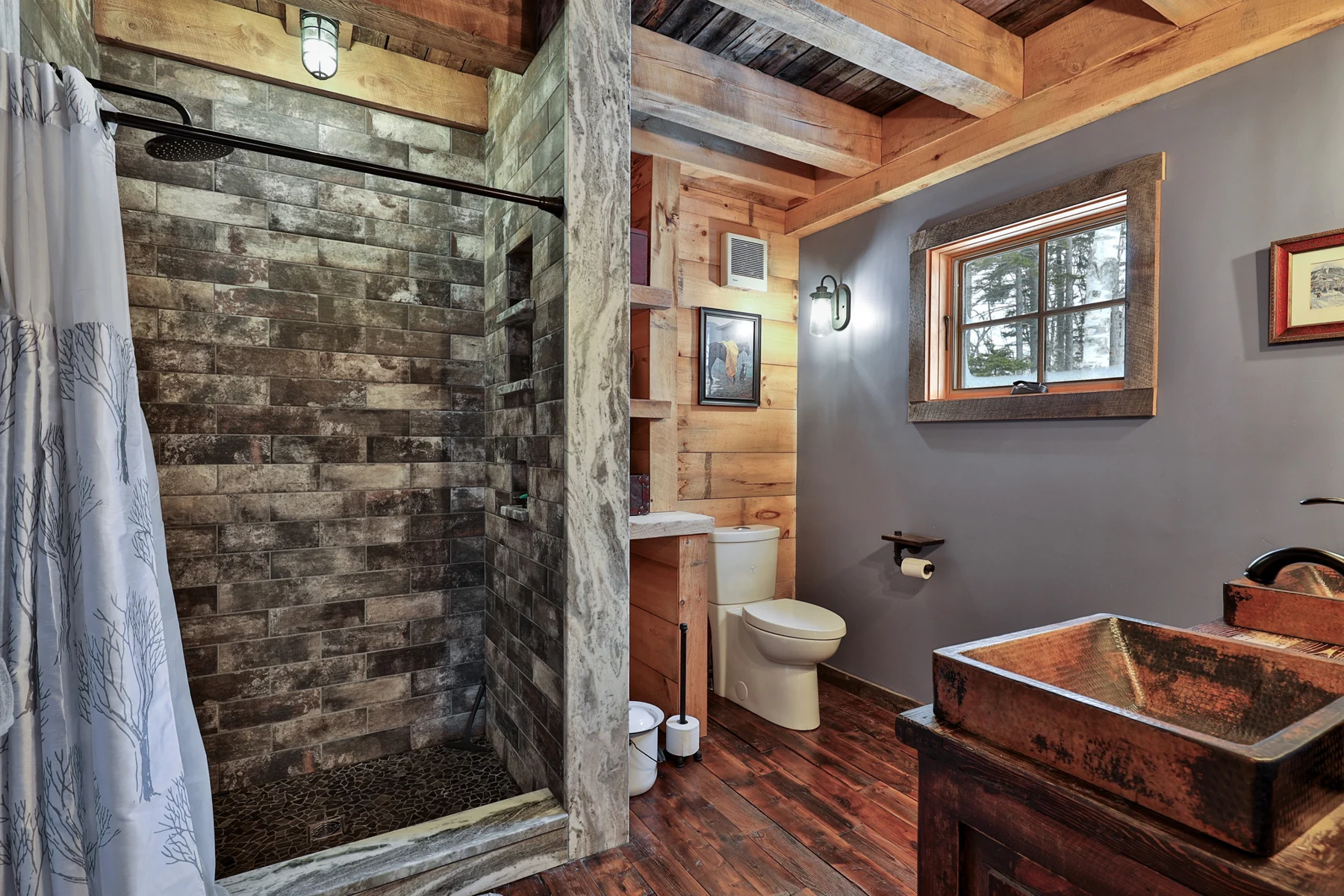 Rustic bathroom with a stone shower, wood vanity and exposed beams in a Hudson Design and Build ski home near Killington, Vermont.