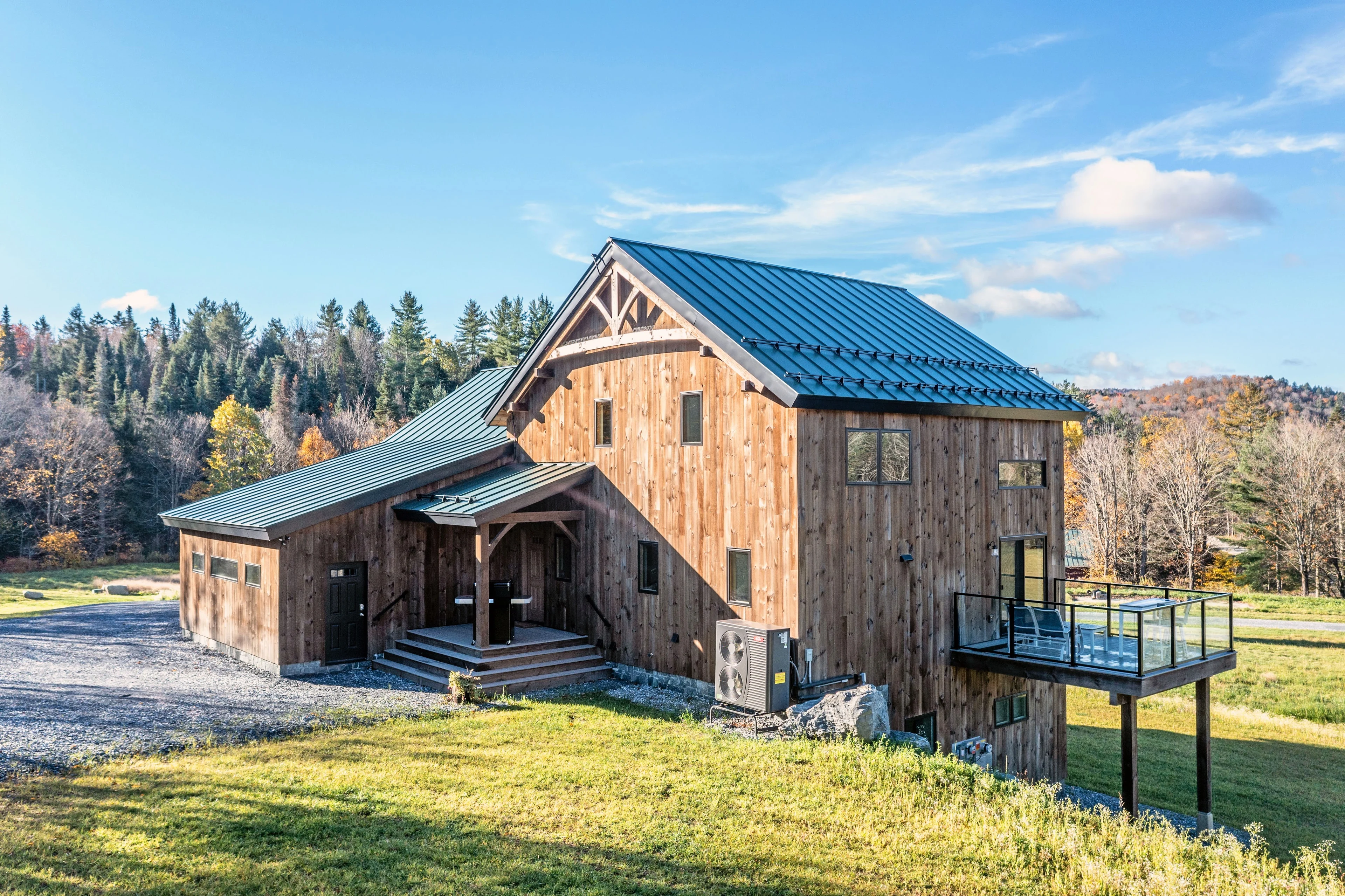 Wood-clad Rochester home with a covered entry, a standing-seam roof and a glass-railed balcony.