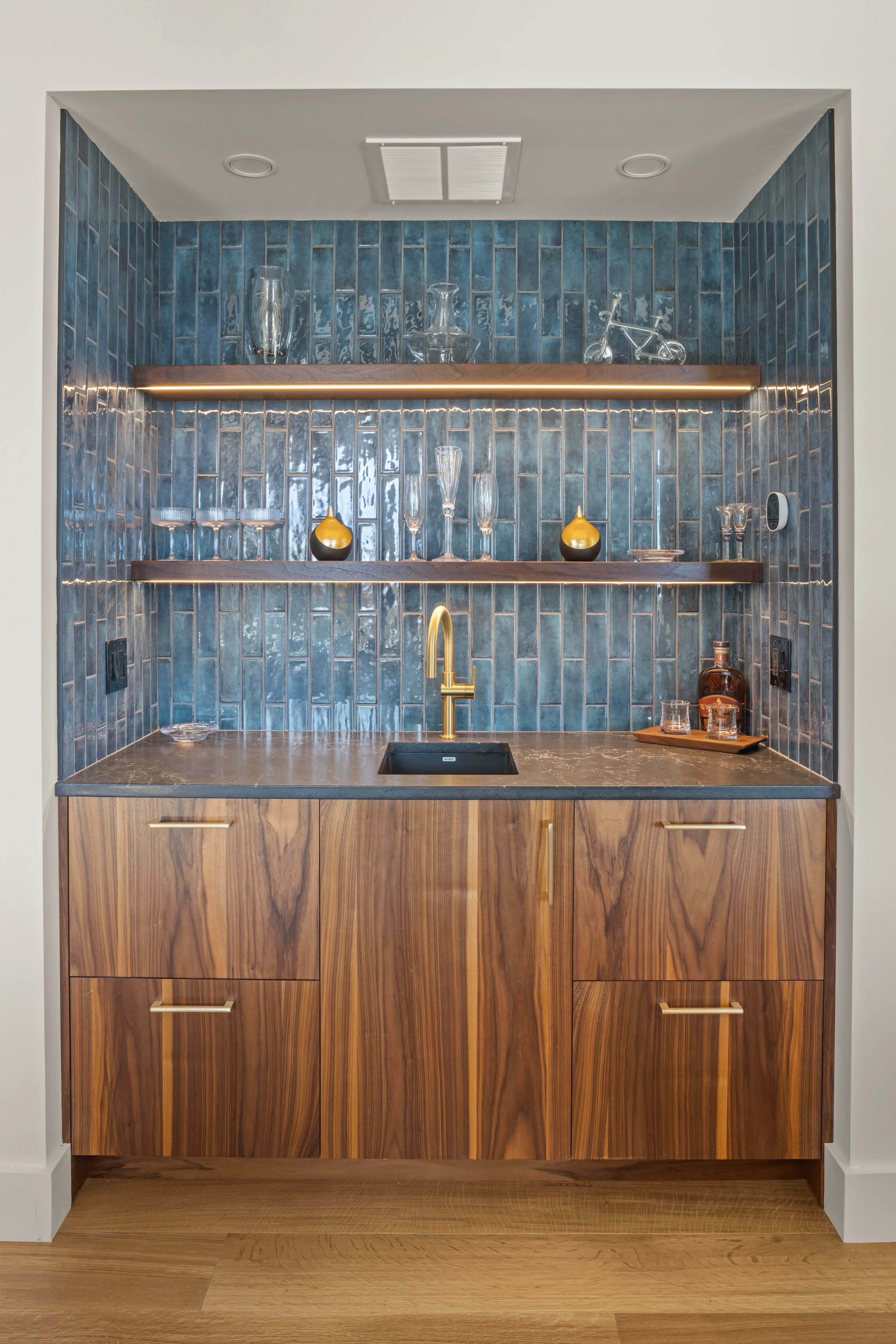Wood bar cabinetry with blue tile, brass fittings and open shelves at Quechee, Vermont.