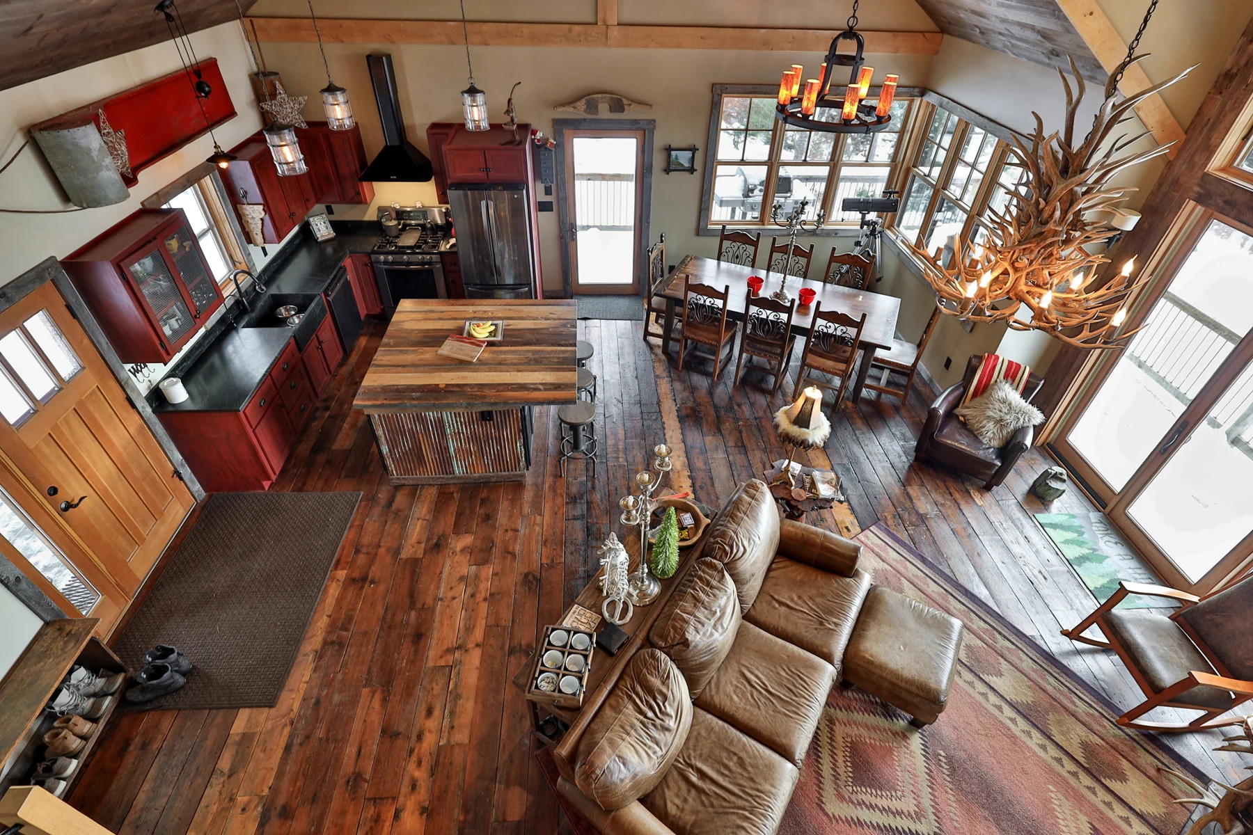 An overhead view of the open kitchen, dining, and living spaces framed by exposed timbers.