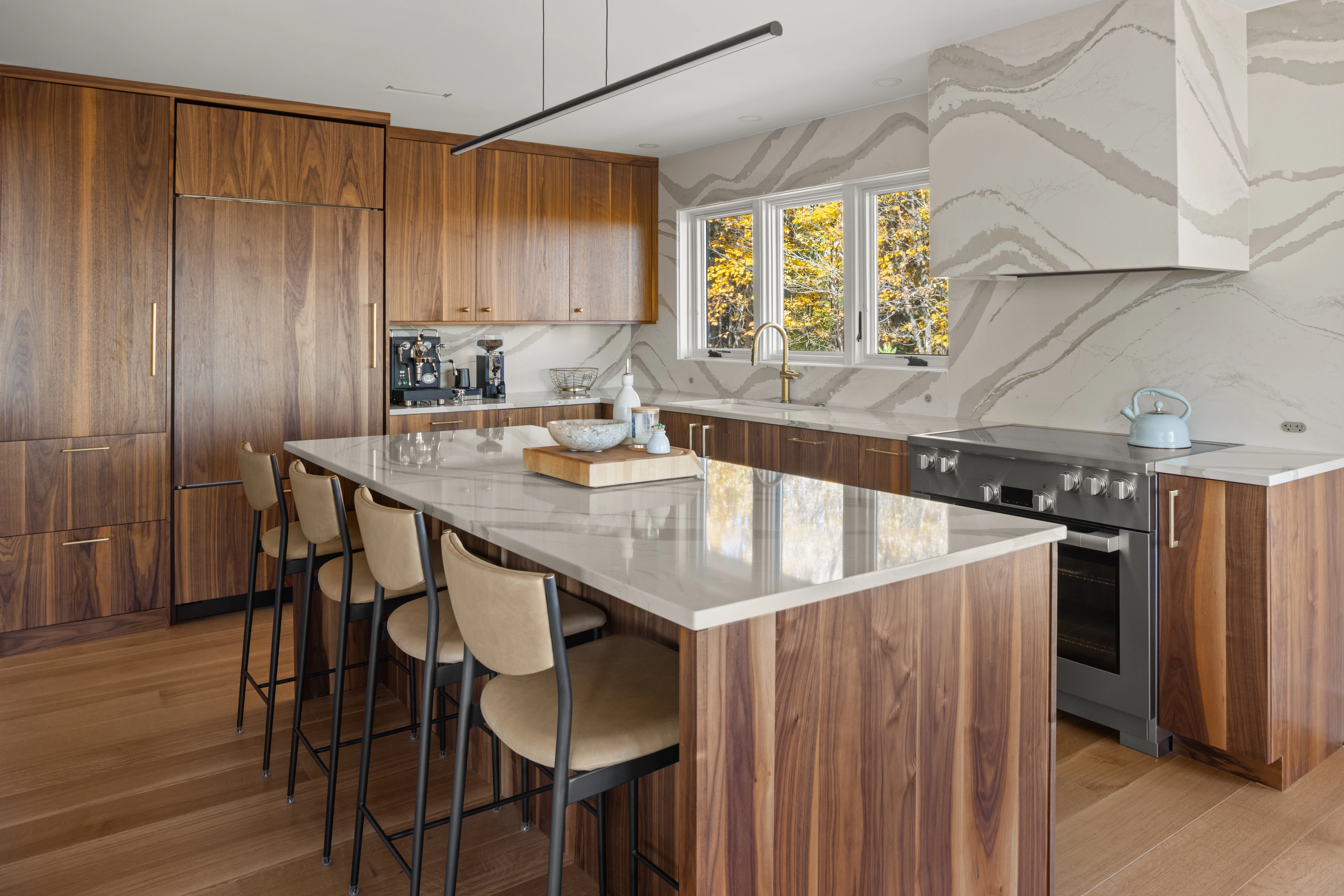 Custom kitchen with wood cabinetry, veined stone surfaces and island seating in Quechee.