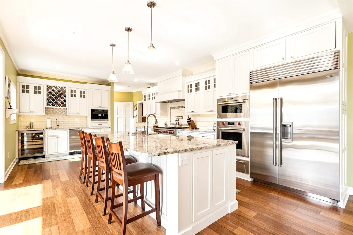 Renovated kitchen with white cabinetry, a stone-topped island and wood floors in Woodstock.