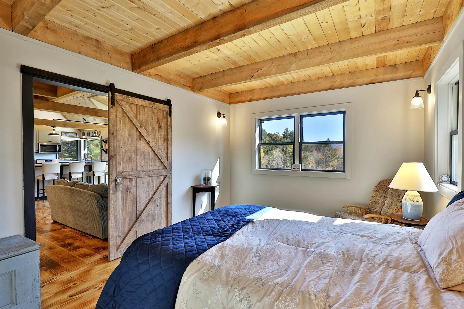 Bedroom with an exposed timber ceiling and sliding barn door in a Hudson Design and Build custom home in Stockbridge, Vermont.