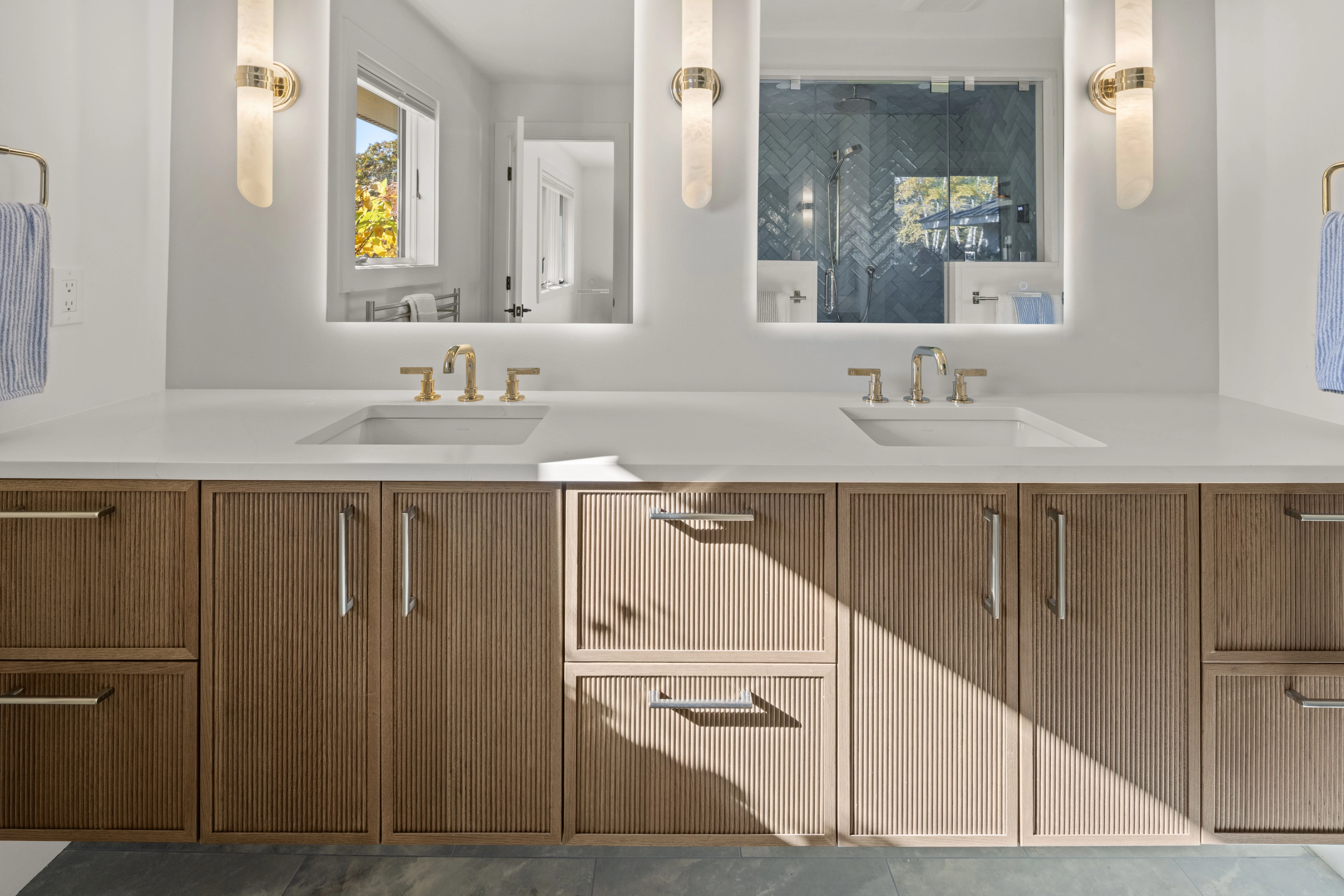 Double vanity with fluted wood cabinetry, wall mirrors and pendant lights in Quechee.