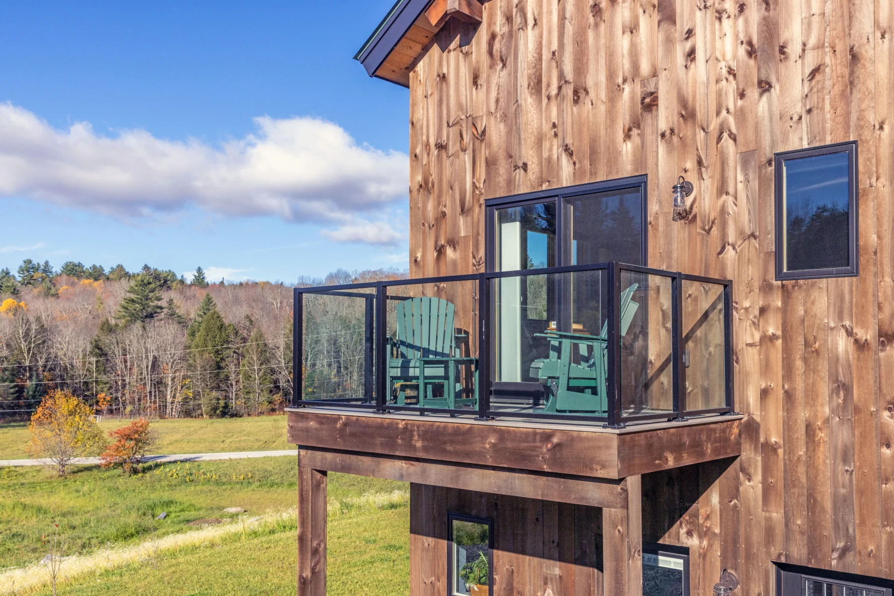 Glass-railed balcony and natural wood siding on a Hudson Design and Build timber frame home in Rochester, Vermont.