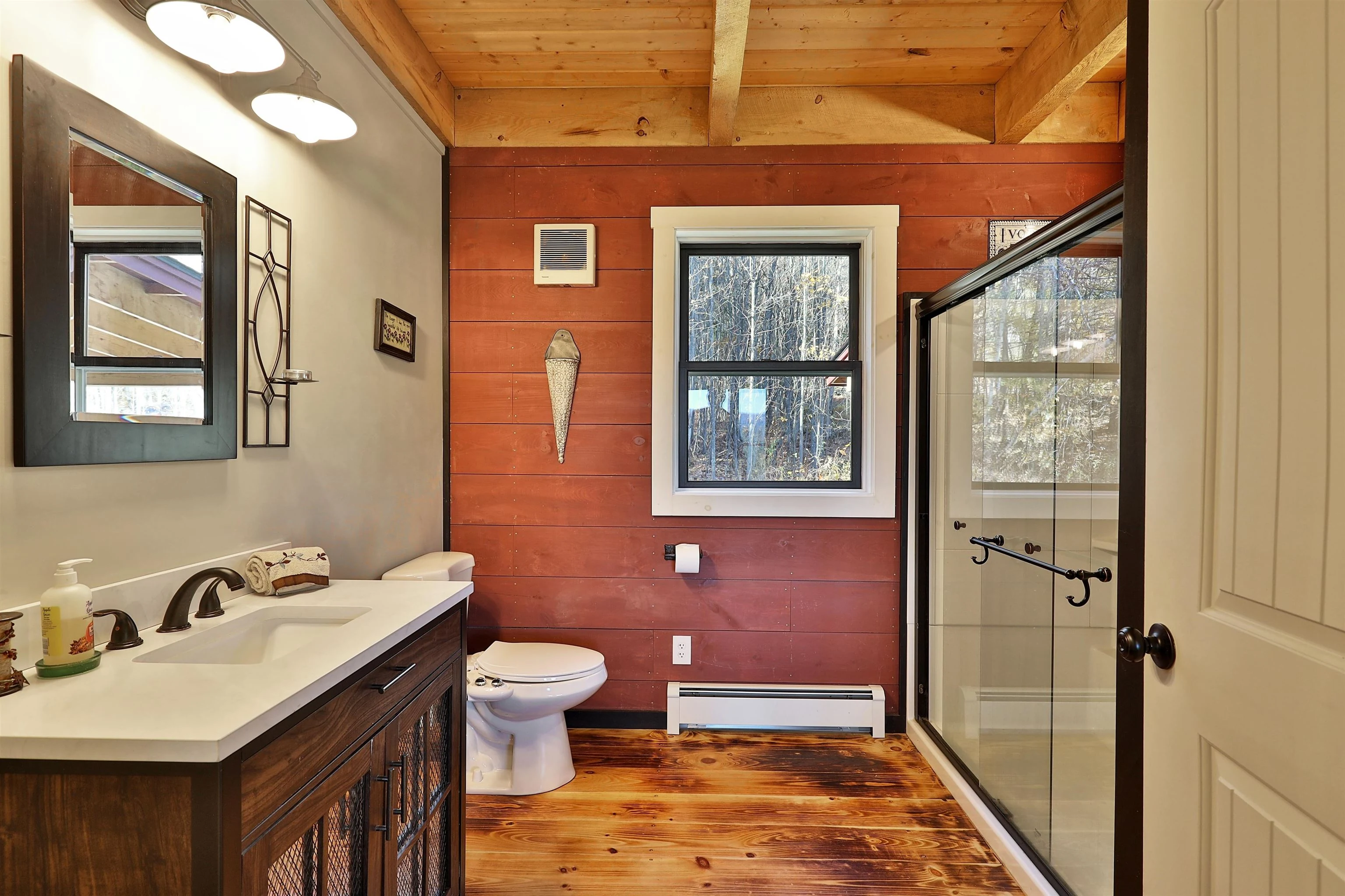 Warm wood ceiling, a red accent wall and a glass shower in a Stockbridge bathroom.