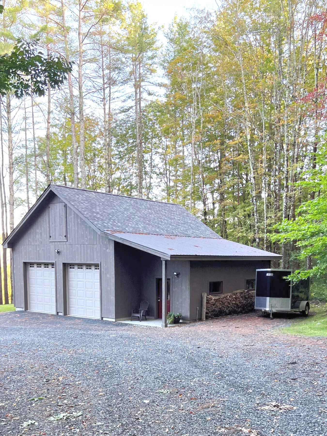 Detached wood-clad barn and garage beside woodland in Woodstock.