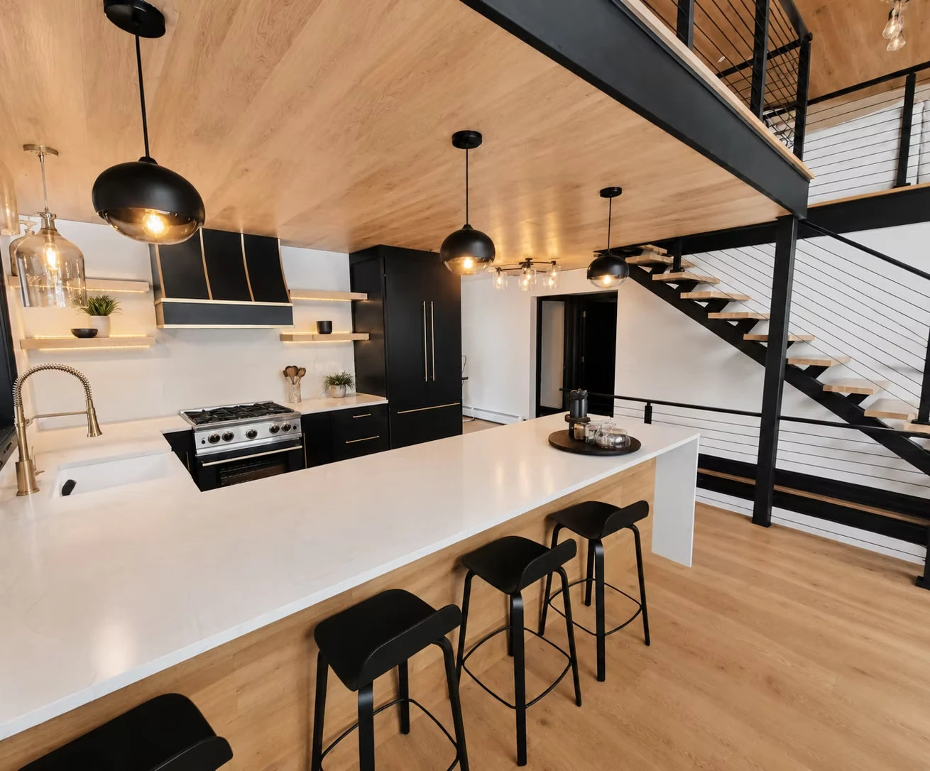 Modern kitchen with black cabinetry, a wood ceiling and an open stair at Woodstock, Vermont.
