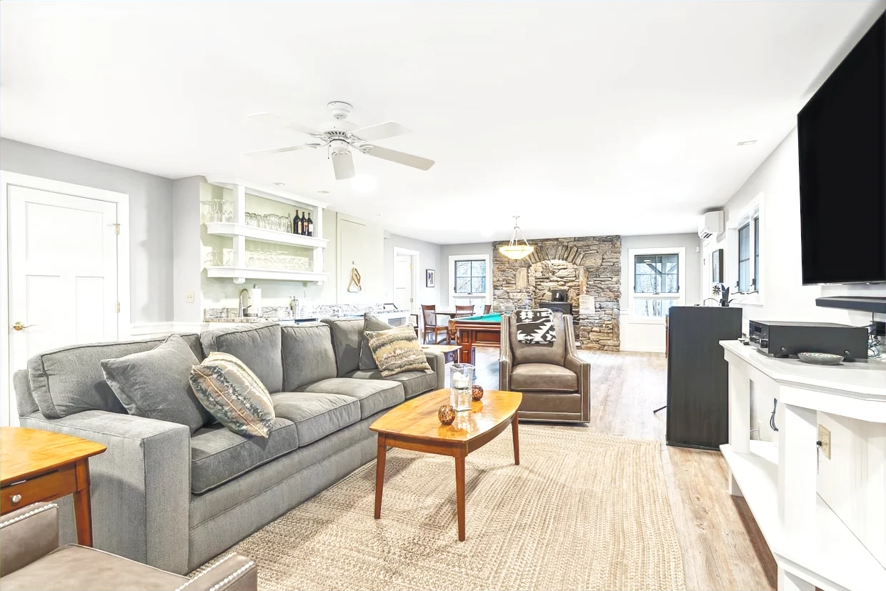 Finished lower-level lounge with a sectional sofa and bright windows in a Hudson Design and Build renovation on Westerdale Road, Woodstock, Vermont.