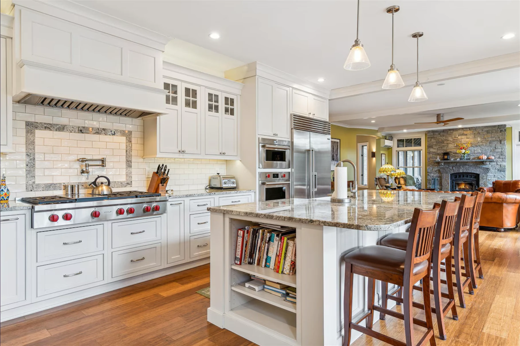 White kitchen with detailed cabinetry, a large island, glass-front upper cabinets and a stainless steel range.