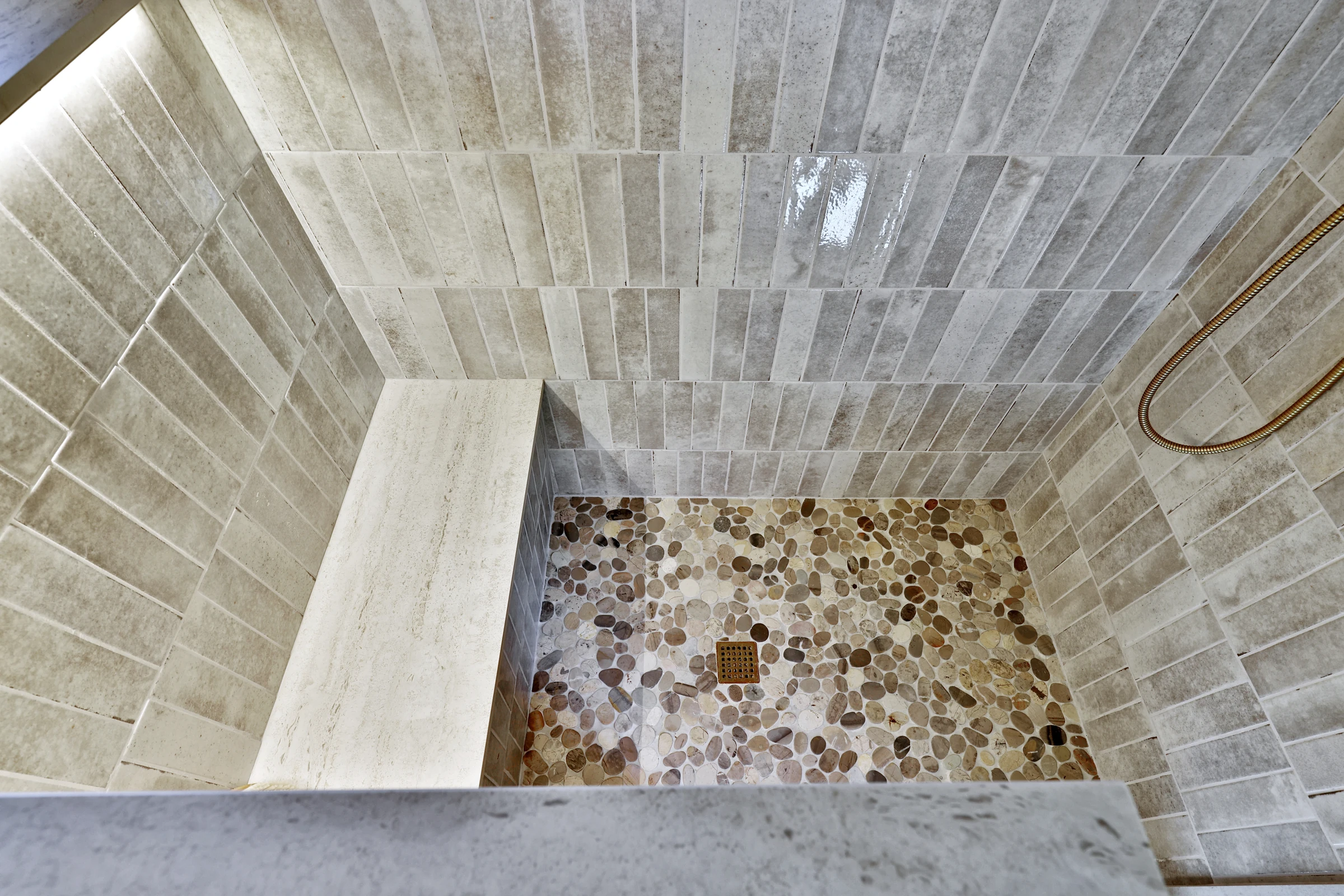 Stone-look shower wall tile meeting a pebble-pattern floor in the Killington home.