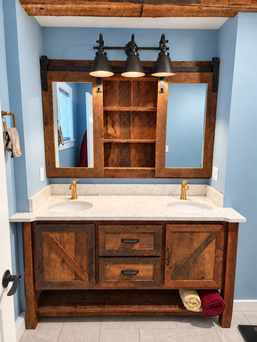 Custom vanity built from reclaimed Stockbridge barn siding, with a white stone top, blue walls and a wood-framed mirror.