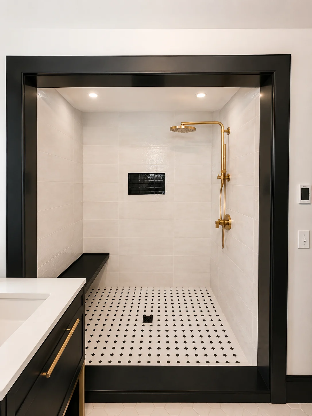 Walk-in shower with light tile, black trim and brass-tone fixtures in a Hudson Design and Build renovation on South Street, Woodstock, Vermont.