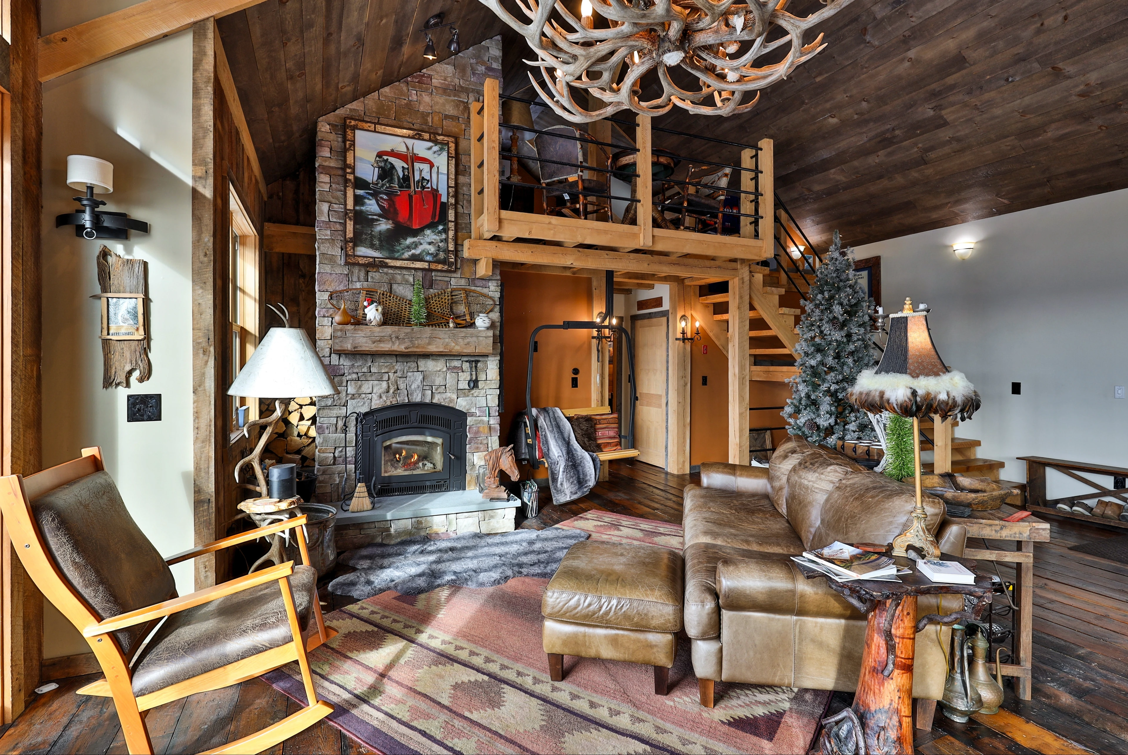 Rustic timber interior with a stone fireplace, wood walls and leather seating at Stockbridge, Vermont.