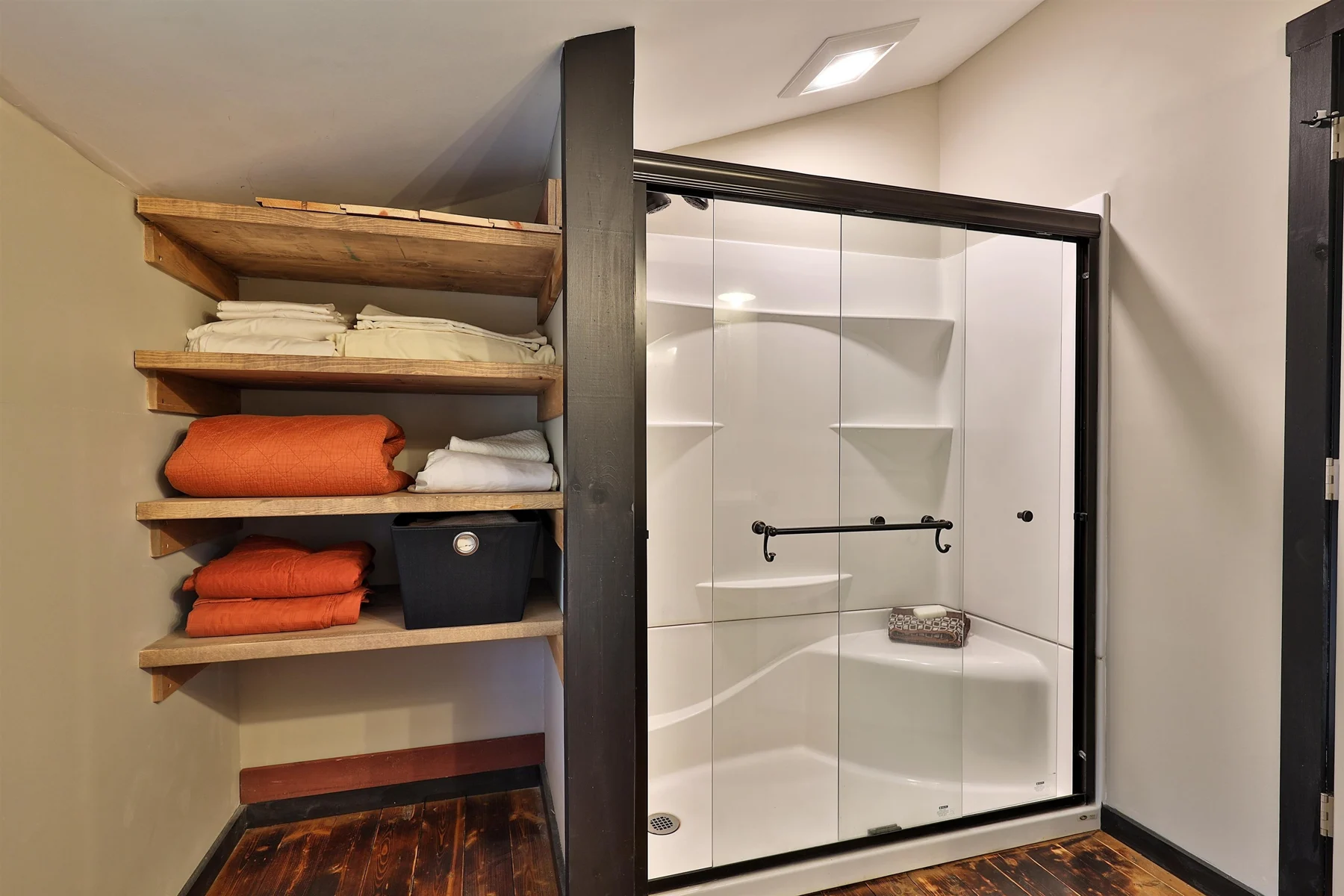 Glass shower enclosure and open wood towel shelves in a Hudson Design and Build timber frame home's bathroom in Stockbridge, Vermont.
