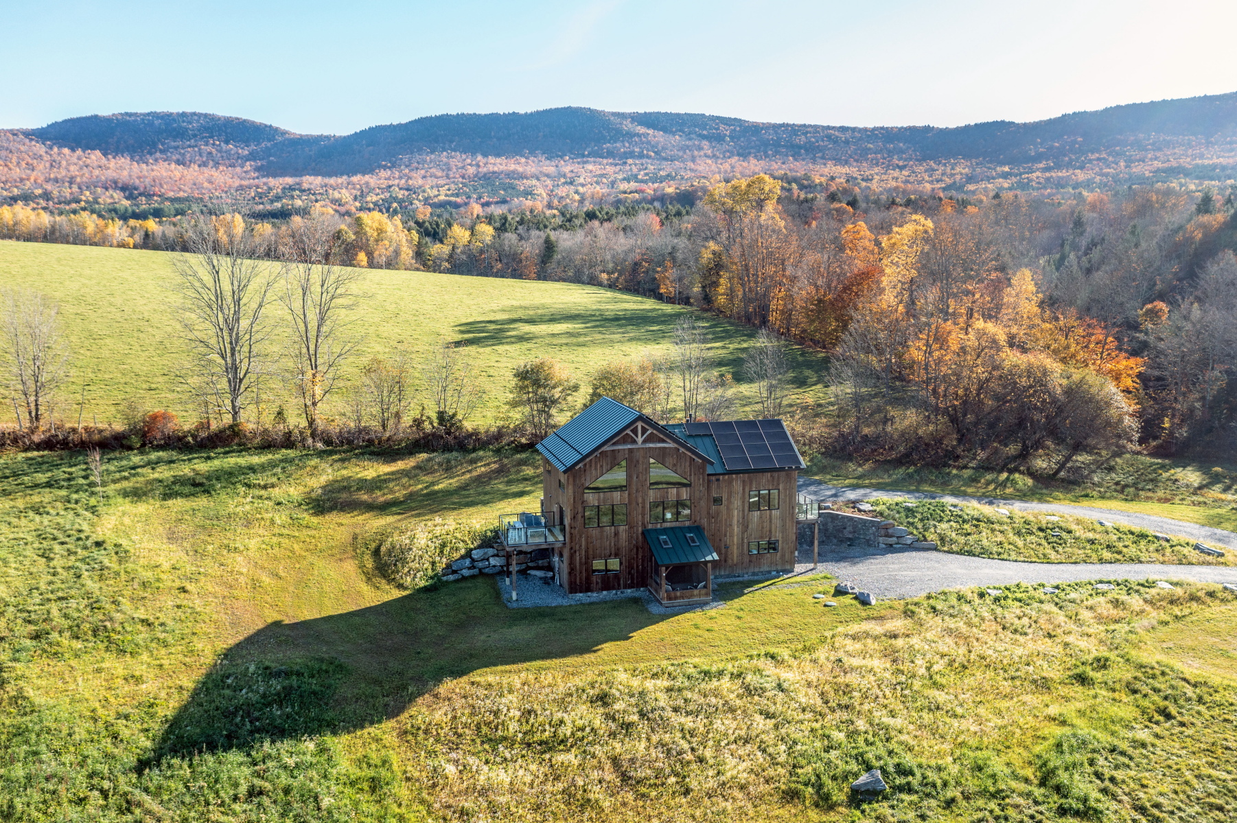 Hudson Design and Build timber frame home in a meadow surrounded by autumn hills in Rochester, Vermont.
