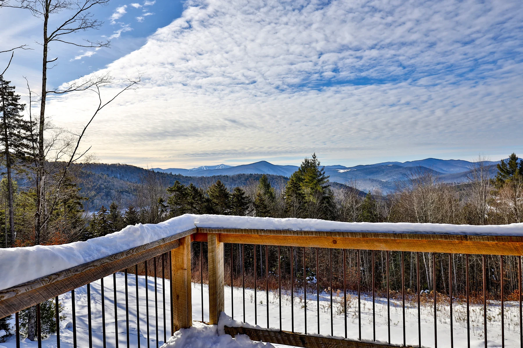 Snow-covered wood deck overlooking Vermont mountain ridgelines at a Hudson Design and Build ski home in the Killington area.