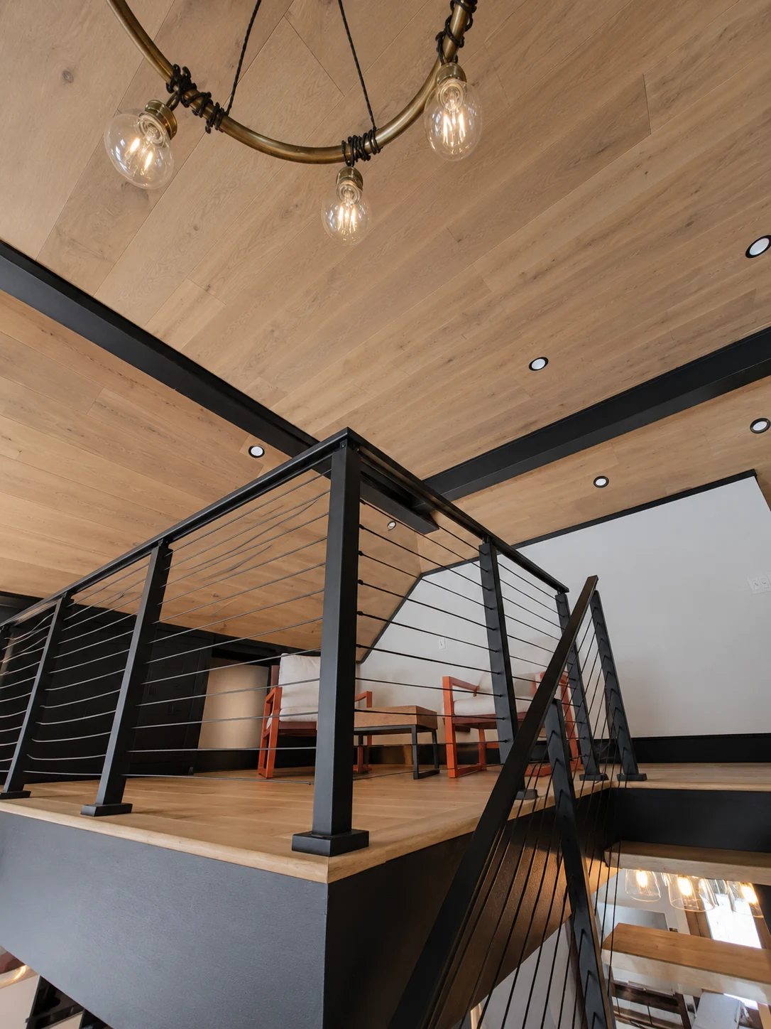 Loft with a wood ceiling, exposed dark beams and cable railings in a Hudson Design and Build renovation on South Street, Woodstock, Vermont.