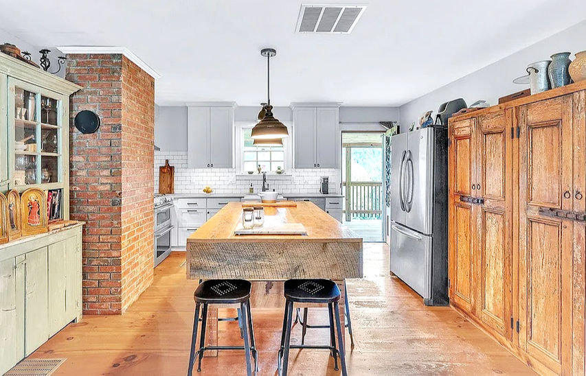 Modern kitchen with wood island and brick accent wall