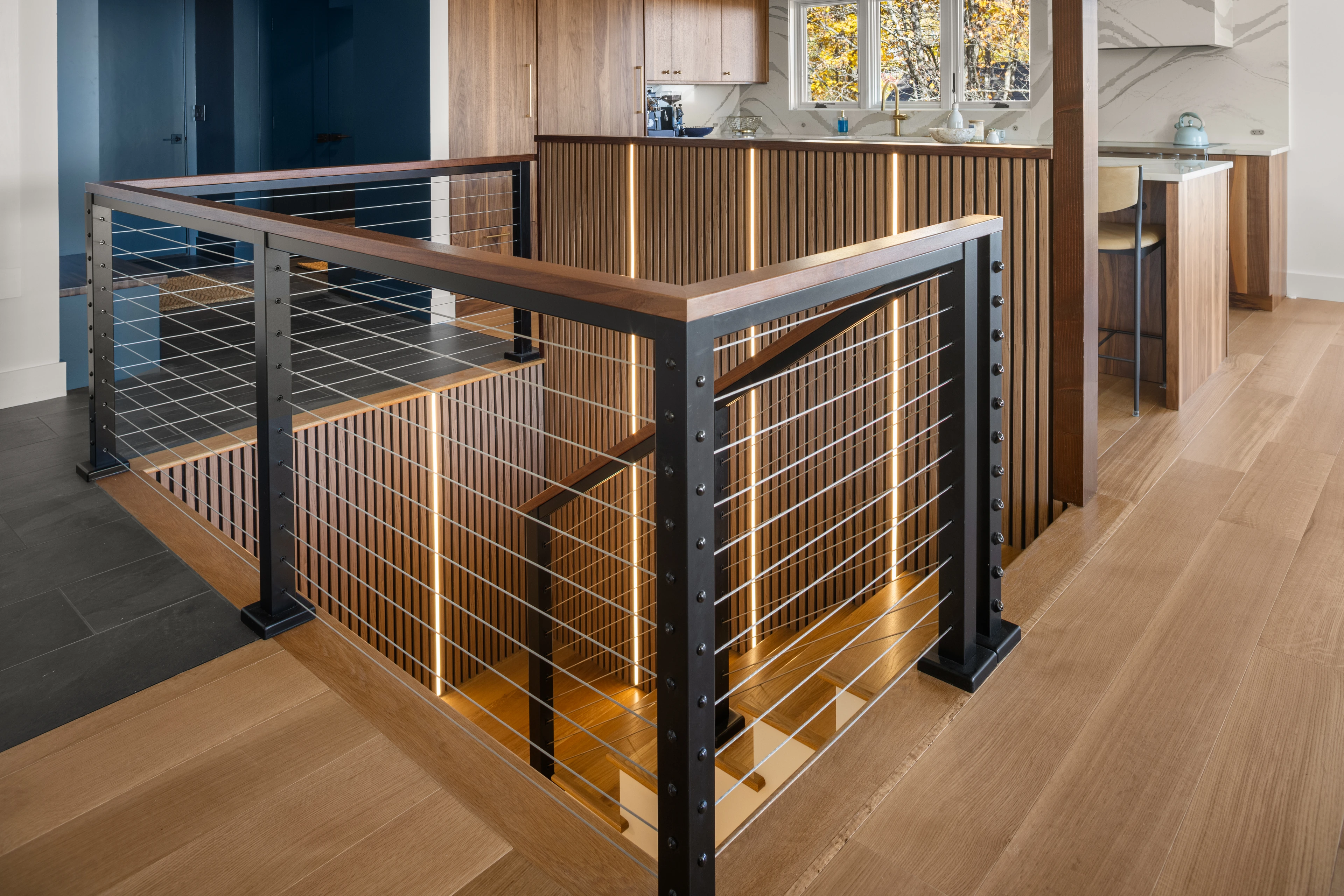 Wood stair opening with dark steel posts and cable railing at Quechee, Vermont.