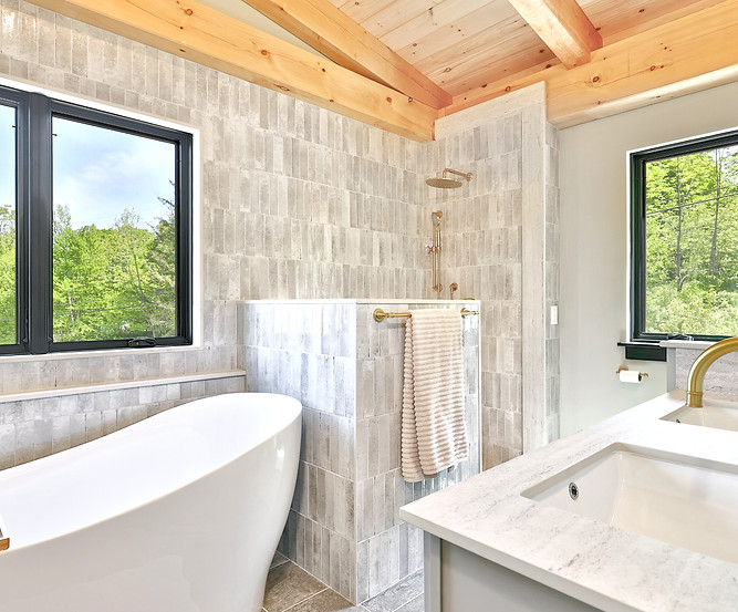 Spa-style bathroom with freestanding soaking tub, walk-in tile shower, and natural finishes in a custom Vermont timber frame home.